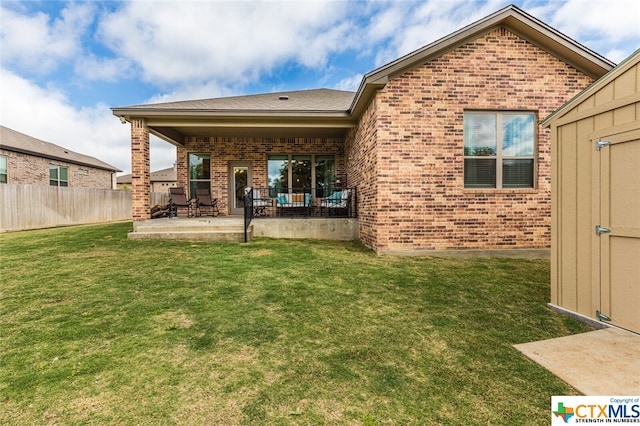 back of property featuring a patio, a lawn, and a storage unit