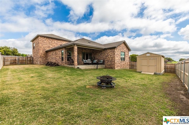 back of property with an outdoor fire pit, a patio, brick siding, a storage unit, and an outbuilding