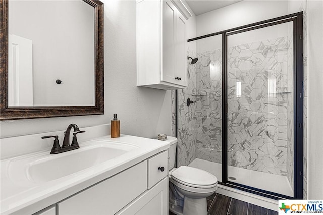 full bathroom featuring a marble finish shower, toilet, vanity, and wood finished floors