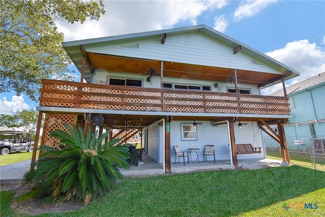 back of property with fence, a ceiling fan, a patio area, and a yard