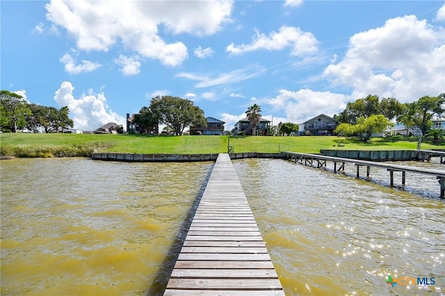 view of dock with a water view and a lawn