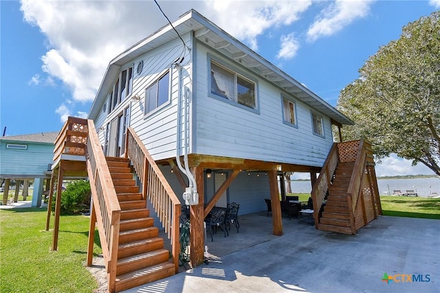 exterior space with stairs, a water view, a patio area, and a lawn