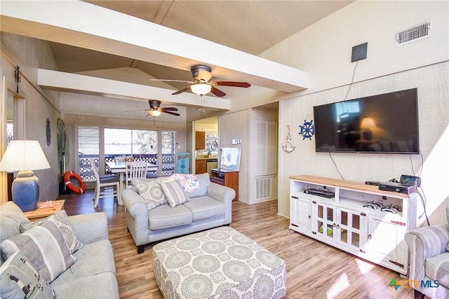 living room with a ceiling fan, wood finished floors, lofted ceiling, and visible vents