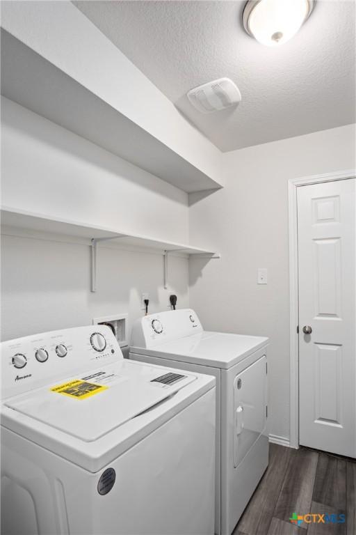 washroom featuring dark wood-type flooring, a textured ceiling, and washing machine and clothes dryer