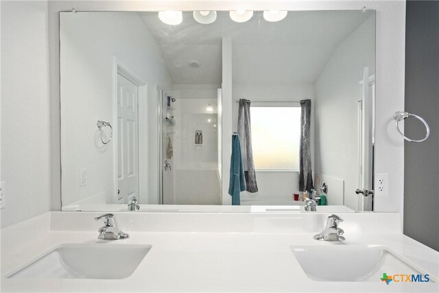 bathroom with a shower with shower door, vanity, and lofted ceiling