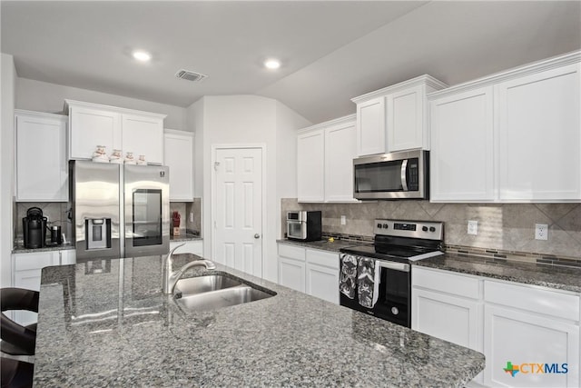 kitchen featuring white cabinets, stainless steel appliances, an island with sink, tasteful backsplash, and sink