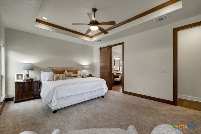 carpeted bedroom featuring crown molding, a barn door, ceiling fan, and a raised ceiling