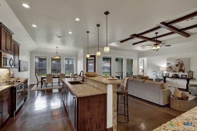 kitchen with a textured ceiling, sink, pendant lighting, and appliances with stainless steel finishes