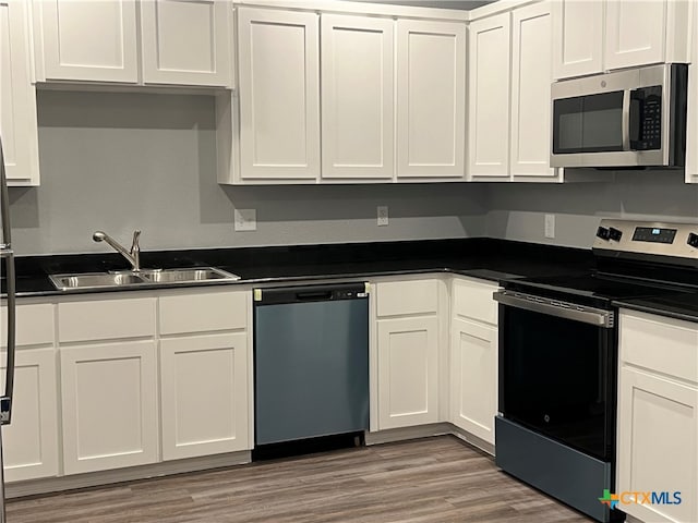 kitchen with sink, white cabinets, light wood-type flooring, and appliances with stainless steel finishes