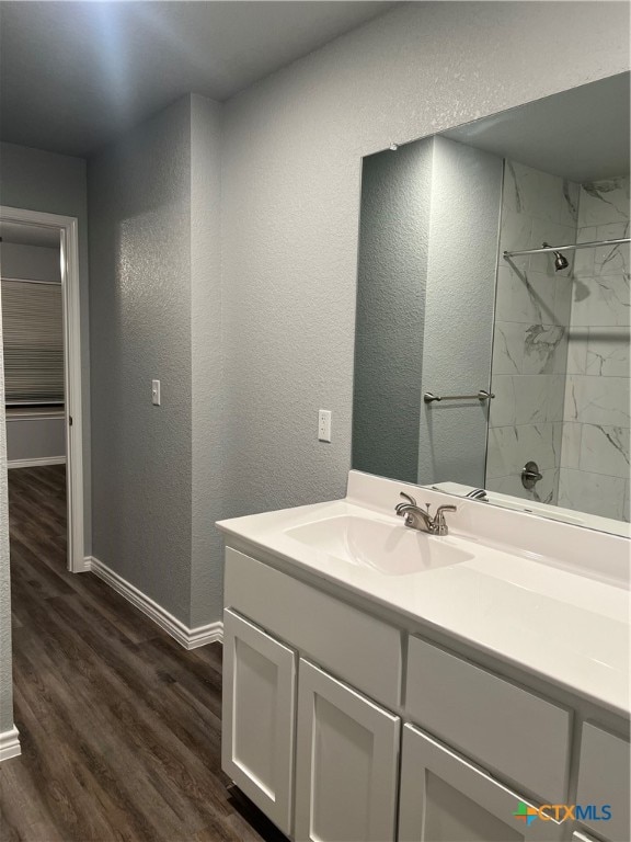 bathroom with a tile shower, vanity, and hardwood / wood-style flooring