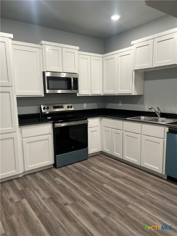 kitchen featuring appliances with stainless steel finishes, dark hardwood / wood-style flooring, white cabinetry, and sink