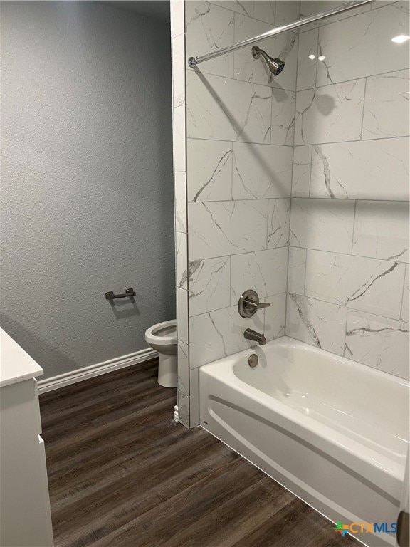 full bathroom featuring vanity, wood-type flooring, tiled shower / bath combo, and toilet