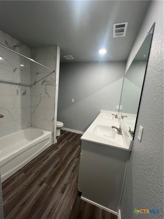 full bathroom featuring toilet, vanity, tiled shower / bath combo, and hardwood / wood-style flooring