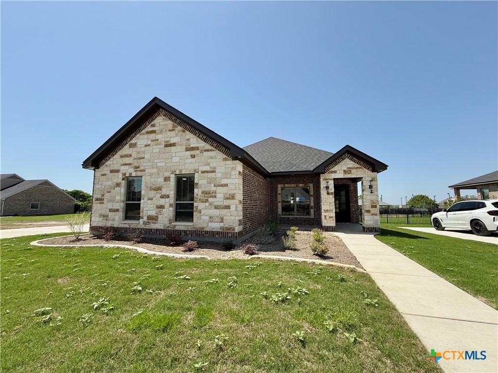 french provincial home featuring a front lawn and stone siding