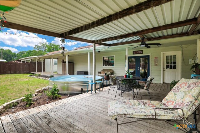 deck featuring a ceiling fan, fence, a yard, french doors, and a hot tub
