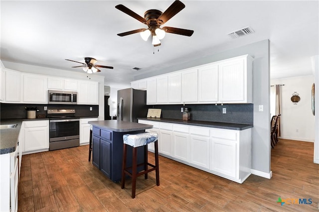 kitchen with dark countertops, visible vents, backsplash, ceiling fan, and appliances with stainless steel finishes