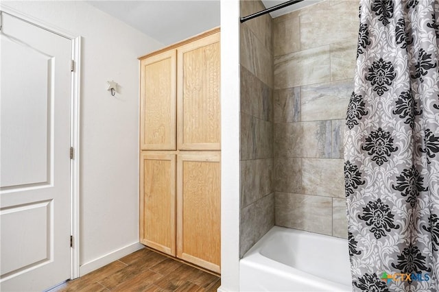 bathroom featuring shower / bath combination with curtain, baseboards, and wood finished floors