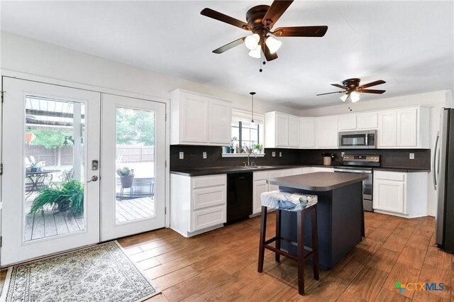 kitchen with a ceiling fan, appliances with stainless steel finishes, tasteful backsplash, and dark countertops