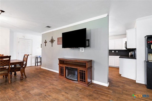 dining space with baseboards, crown molding, visible vents, and dark wood-style floors