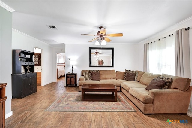 living room featuring visible vents, a ceiling fan, wood finished floors, and crown molding