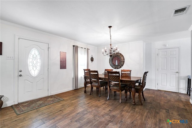dining room featuring a chandelier, dark wood finished floors, baseboards, ornamental molding, and visible vents
