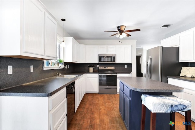 kitchen with a sink, dark countertops, visible vents, a ceiling fan, and appliances with stainless steel finishes