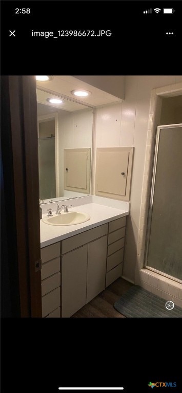 bathroom featuring vanity, an enclosed shower, and wood-type flooring