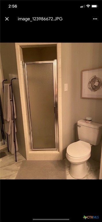 bathroom featuring toilet and a shower with shower door