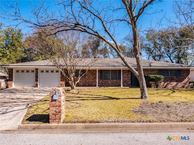 ranch-style home featuring a front lawn, concrete driveway, brick siding, and a garage