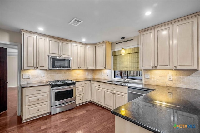 kitchen with sink, dark hardwood / wood-style flooring, pendant lighting, stainless steel appliances, and decorative backsplash