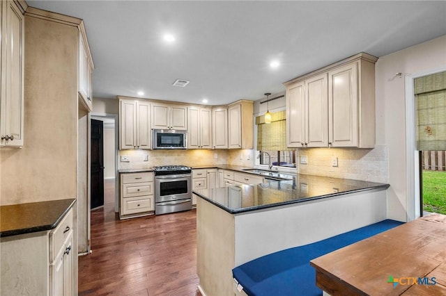 kitchen featuring sink, appliances with stainless steel finishes, tasteful backsplash, decorative light fixtures, and kitchen peninsula