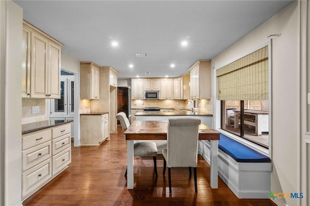 kitchen featuring a kitchen bar, sink, tasteful backsplash, dark hardwood / wood-style floors, and stainless steel appliances