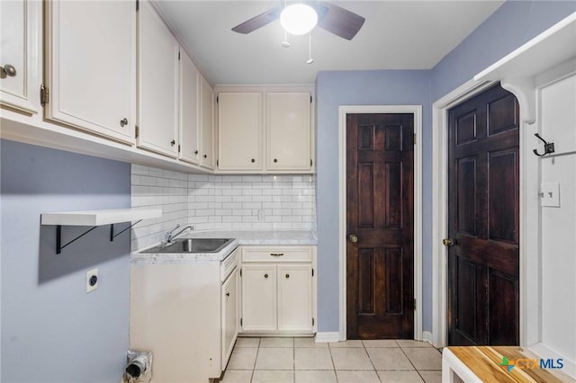 kitchen with tasteful backsplash, sink, light tile patterned floors, and white cabinets