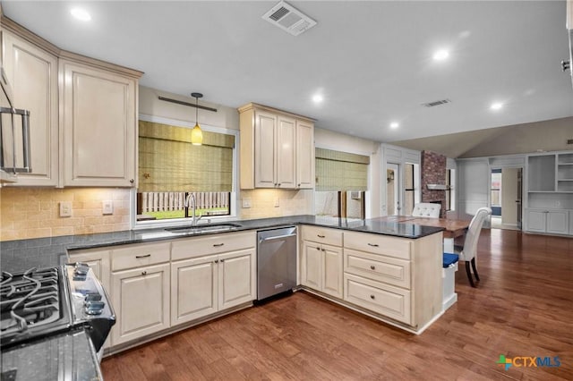 kitchen featuring hardwood / wood-style floors, pendant lighting, dishwasher, sink, and kitchen peninsula