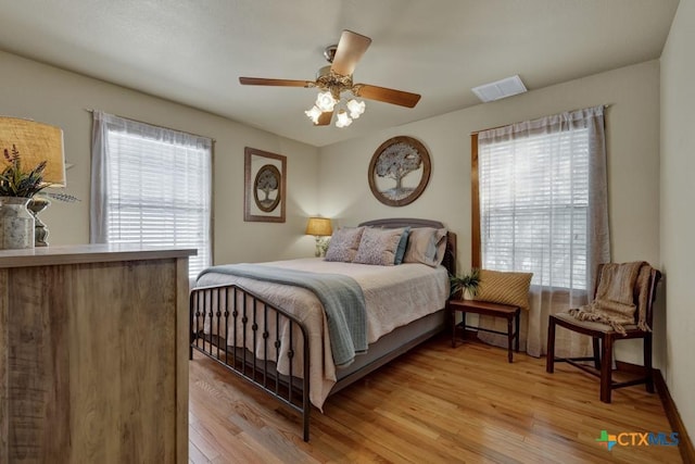 bedroom with light wood-type flooring, multiple windows, and ceiling fan