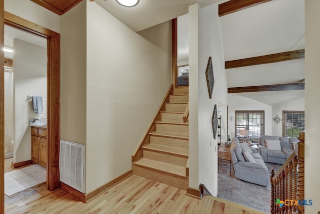 stairway featuring hardwood / wood-style floors and lofted ceiling with beams