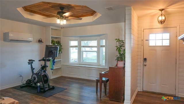 entrance foyer featuring a wall mounted air conditioner, dark hardwood / wood-style floors, and a raised ceiling