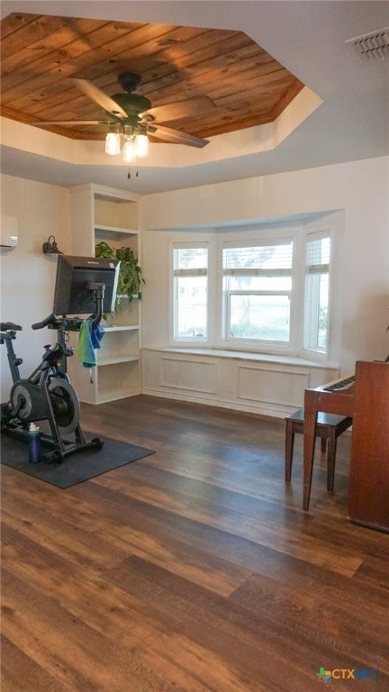 exercise room with dark hardwood / wood-style floors, a raised ceiling, ceiling fan, and wood ceiling