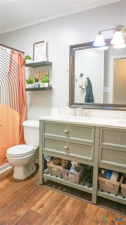 bathroom featuring ornamental molding, vanity, wood-type flooring, toilet, and curtained shower