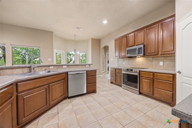 2291 Frontier, Spring Branch, TX 78070 - kitchen with appliances with stainless steel finishes, tasteful backsplash, brown cabinetry, and recessed lighting
