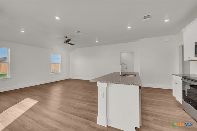 kitchen featuring white cabinets, light hardwood / wood-style floors, sink, and a kitchen island with sink