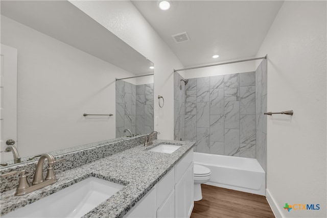 full bathroom featuring hardwood / wood-style floors, vanity, toilet, and tiled shower / bath