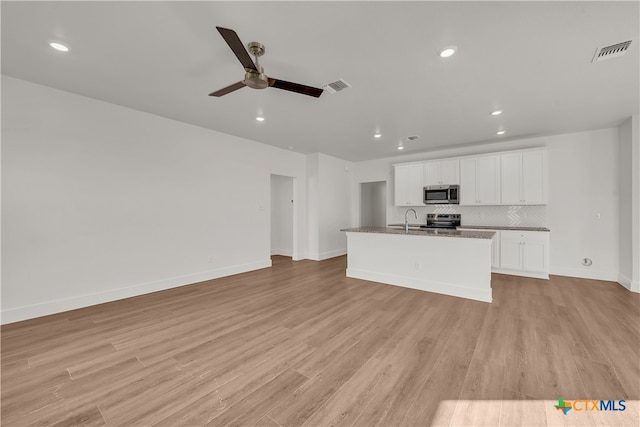 kitchen featuring white cabinets, stainless steel appliances, light hardwood / wood-style flooring, and an island with sink