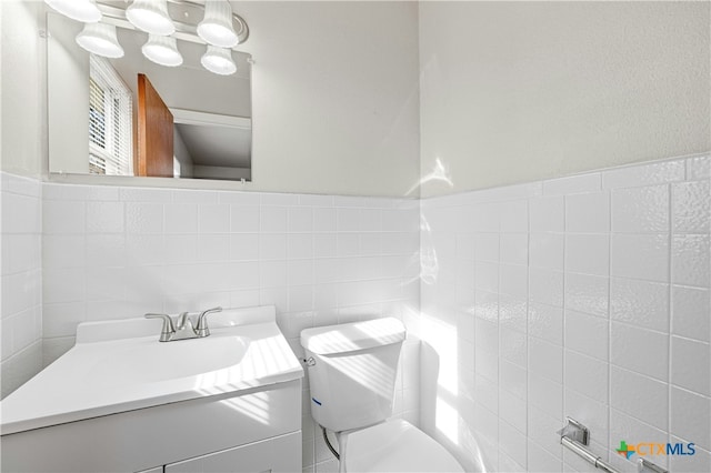 bathroom with vanity, toilet, and tile walls