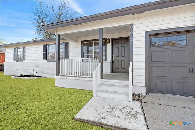 view of exterior entry with a lawn and a porch