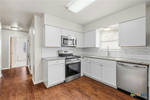 kitchen with appliances with stainless steel finishes, white cabinetry, dark wood-type flooring, and sink