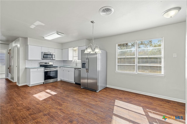 kitchen with hanging light fixtures, stainless steel appliances, dark hardwood / wood-style flooring, decorative backsplash, and white cabinets