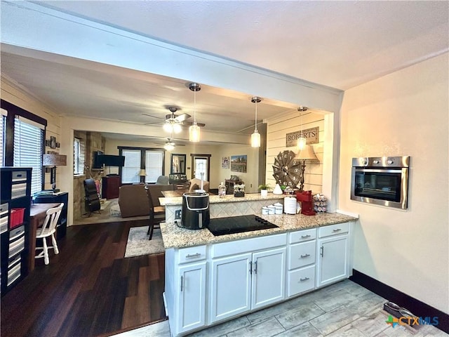 kitchen with pendant lighting, white cabinets, oven, black electric stovetop, and light stone counters