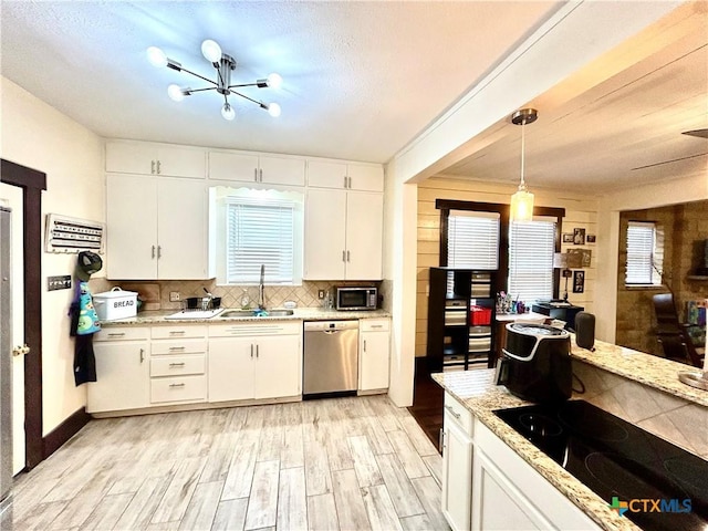 kitchen with pendant lighting, appliances with stainless steel finishes, sink, and white cabinets