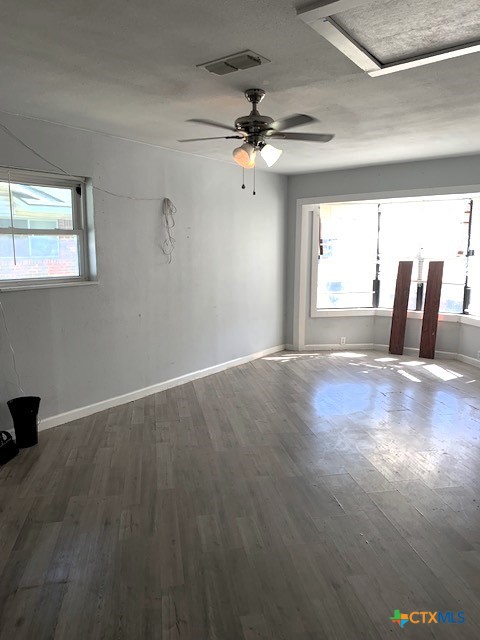 spare room with plenty of natural light, ceiling fan, and wood-type flooring